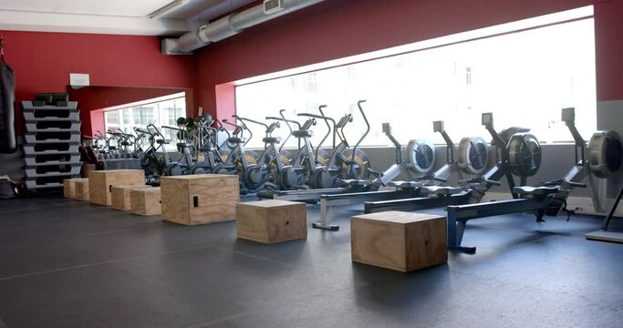 A modern gym with rows of stationary bikes and rowing machines