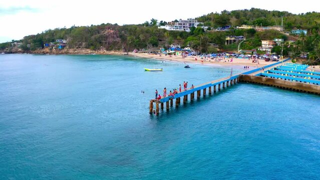Drone footage of people on the dock jumping in water near the beach in Puerto Rico