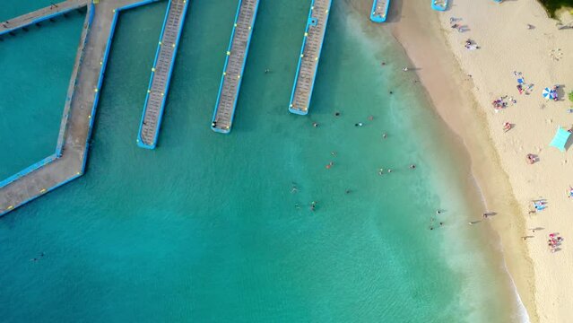 Aerial above beautiful beach with a dock, greenery and people enjoying the summertime in Puerto Rico