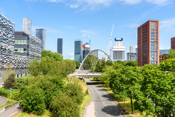Modern bridge over a street leading to Manchester city centre on a sunny spring day. Modern Skyscrapers are in background.
