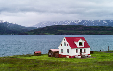 Fototapeta na wymiar a house on the edge of a grassy field near water