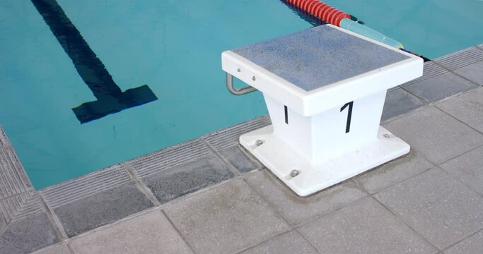 Starting block number one stands ready at a swimming pool's edge
