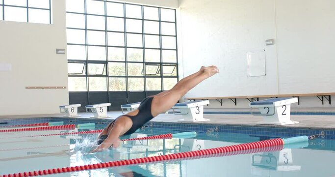 Swimmer dives into a pool at a competition, with copy space