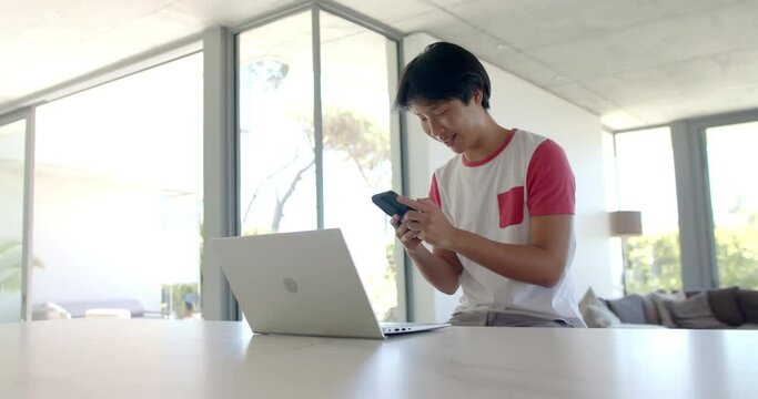Teenage Asian boy studying at a bright home office