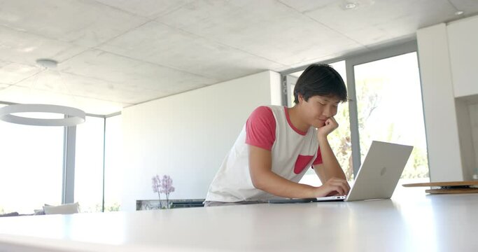 Teenage Asian boy studying intently at a home office with copy space