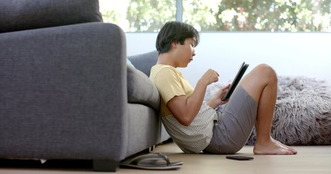 Teenage Asian boy focused on his tablet at home