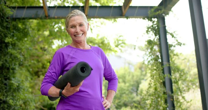 Senior Caucasian woman holding a yoga mat outdoors