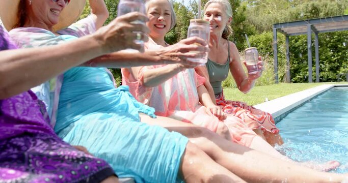 Senior group of women enjoying a toast by the pool outdoors