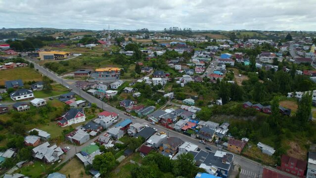 Aerial orbit establishing Chonchi, a small village in Chiloe, Chile. Urbanism with a lot of green areas, coastal town