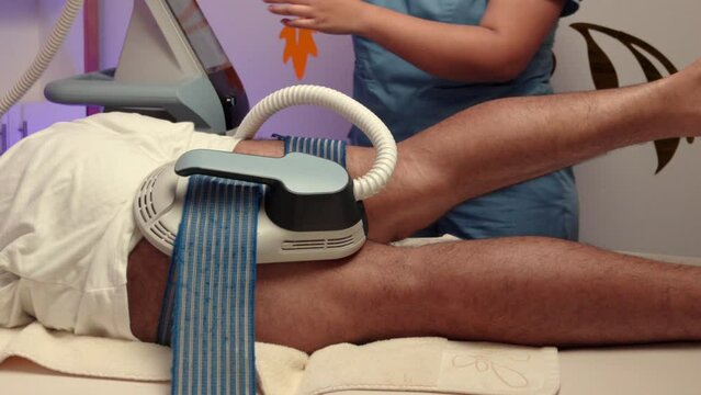 Spa therapist EMS electro stimulation therapy on femoral legs muscle man male muscle muscular vibration waves