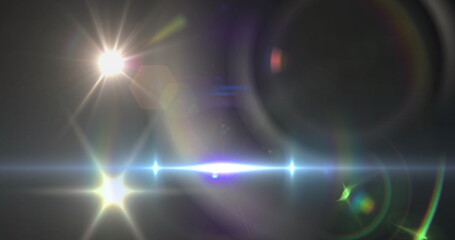 Image of spotlight with lens flare and light beam moving over dark background