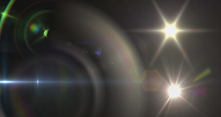 Image of spotlight with lens flare and light beam moving over dark background