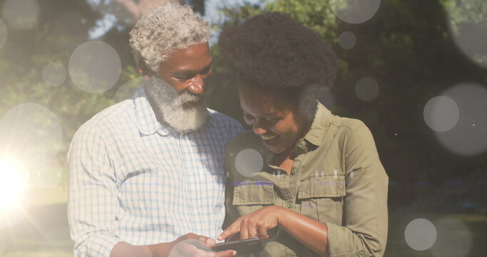 Image of light spots over african american couple using smartphone