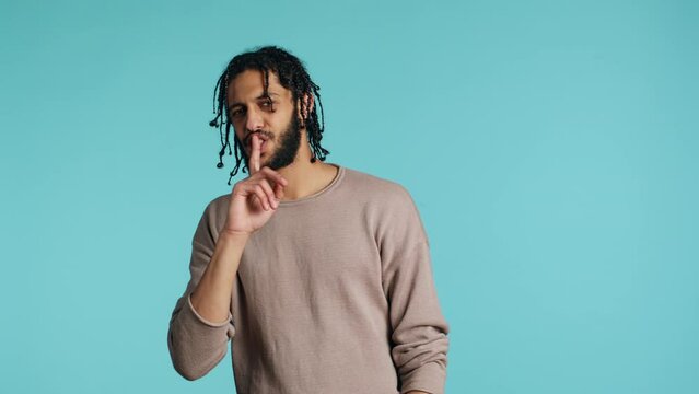 Annoyed middle eastern man doing shushing hand gesturing, irritated by noise, having negative mood. Assertive person placing finger on lips, doing quiet sign gesture, studio background, camera A