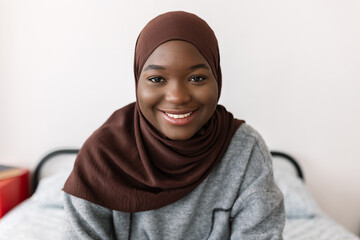 Portrait of young happy african black woman in muslim headscarf at home. Proud of religion and...