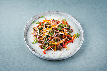 Traditional Asian wok spinach with chestnuts, pepper strips and soy sprouts served as close-up in a Nordic design plate with copy space