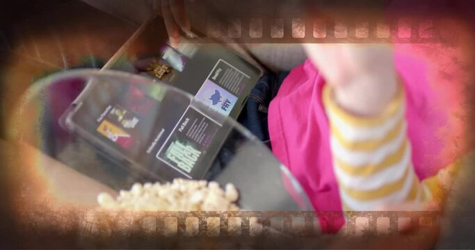 Animation of film frame over midsection of diverse teenage girls using tablet eating popcorn at home