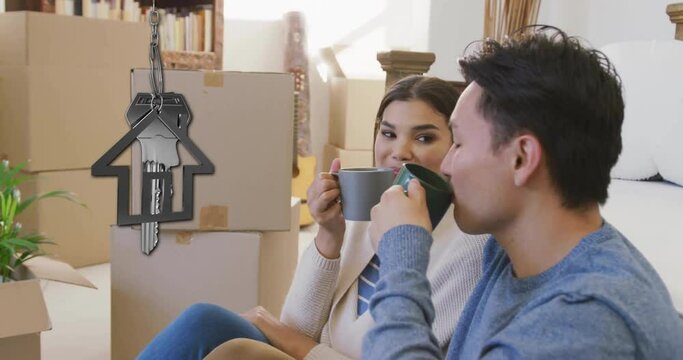Animation of silver house key and key fob over diverse couple drinking tea at new home