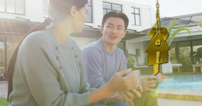 Animation of gold house key and key fob over happy diverse couple in garden at home
