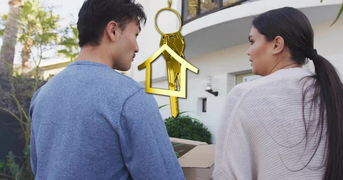 Animation of gold house key and key fob over happy biracial couple by house