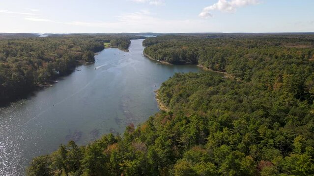 Aerial Drone descending footage of New Meadows river, Bath, Brunswick.  Show heavy forest, River and small boat