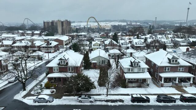 Winter Snow in Hershey Neighborhood with houses and block in background. Cloudy grey sky in winter. Aerial wide trucking shot. Pennsylvania, USA. Hershey Park amusement rides in background.