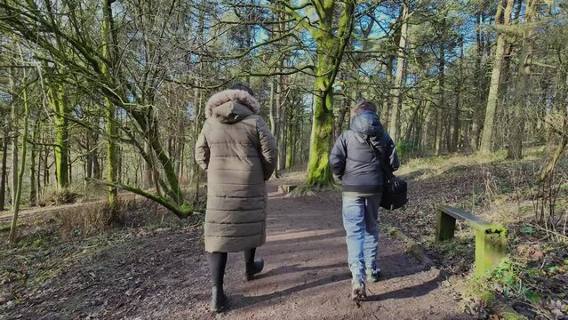 Young boy and his mother walking on a rural footpath on a day out in the forest woodlands. Countryside activity scene with moorlands winter scene