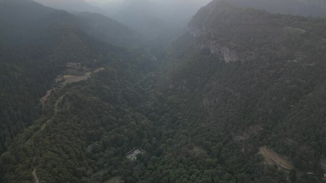 Aerial footage of the dense green woods on the mountains near Indore city on a foggy sunset, India
