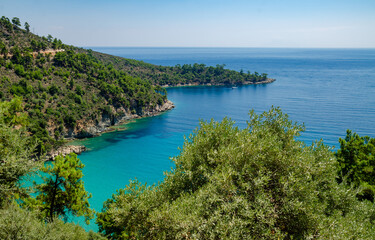 Fototapeta na wymiar Serene blue lake nestled among lush forests and towering mountains in Thassos, Greece
