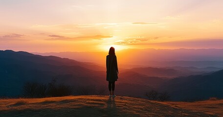 The Elegant Silhouette of a Woman Standing Solitary on a Hill with Mountains Bathed in Sunset