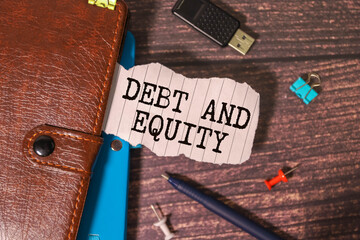 text DEBT EQUITY on easel with office tools and paper. Top view. Business.