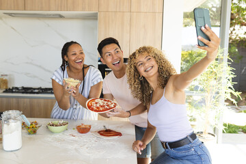 Young Asian man and two biracial women take a selfie in a home kitchen