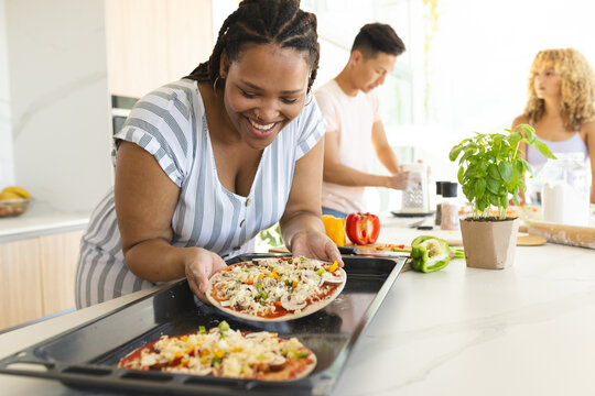 A diverse group prepares pizza in a home kitchen