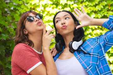 Biracial female friends posing playfully outdoors