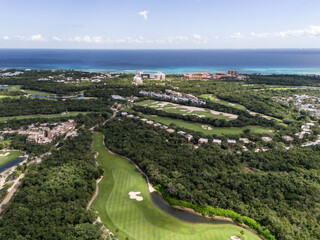 Drone view of green golf course with luxury houses surrounded by green tropical vegetation and...