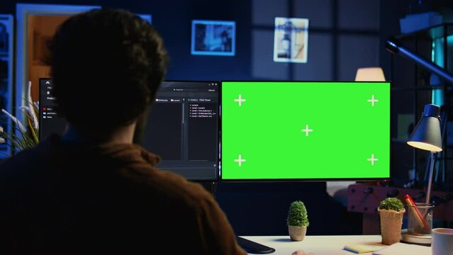 Freelancing man doing IT support job from apartment personal office, coding on isolated screen PC. Software programmer writing lines of code on chroma key computer at home, camera B
