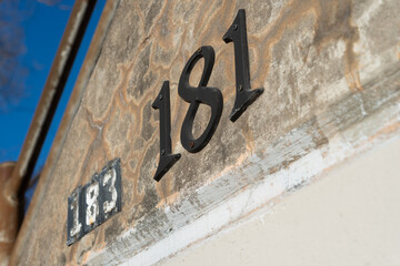 numbers 183 and 181 on the side of a concrete barrier wall with a bit of a blue sky