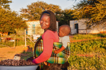 african street vendor selling peanuts, african woman giving a piggyback ride to her child, carry...