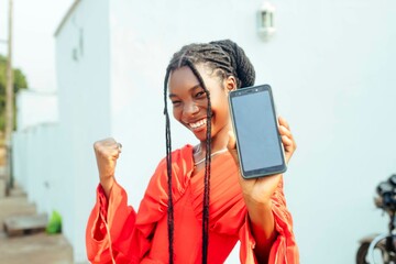 excited black young teenage girl holding mobile phone display at camera 