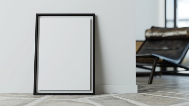 Blank vertical black poster frame standing on the floor against white wall in modern living room, empty picture frame mockup.