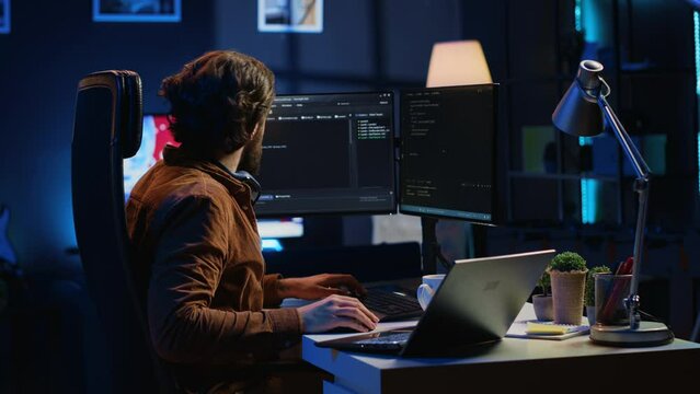 Technician typing code in neon lit personal office, using javascript programming language to develop software application. It specialist using multimonitor desktop setup to finish project, camera A