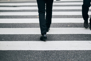 横断歩道を歩くビジネスマンの足元のクローズアップ - obrazy, fototapety, plakaty