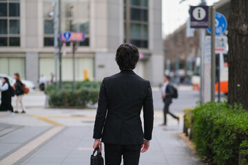 歩道を歩くビジネスマンの後ろ姿のクローズアップ