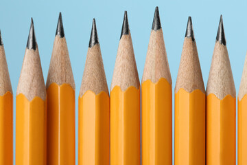 Many sharp graphite pencils on turquoise background, macro view