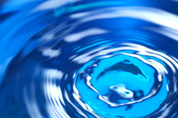 Splash of clear water on blue background, closeup