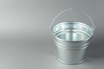 One shiny metal bucket on light grey background. Space for text