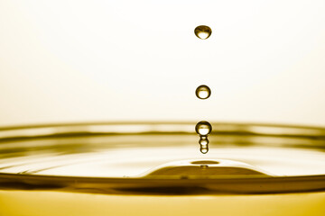 Splash of golden oily liquid with drops on white background, closeup