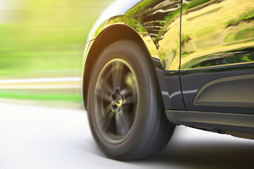 Black car driving on road outdoors, closeup with motion blur effect. Space for text