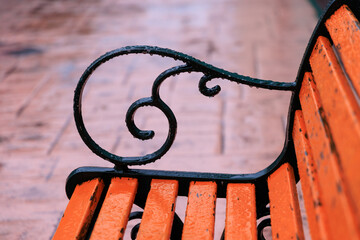 冬の雨の日の遊園地のオレンジ色のベンチ