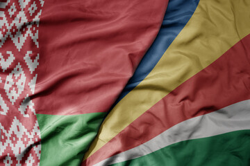 big waving national colorful flag of seychelles and national flag of belarus.
